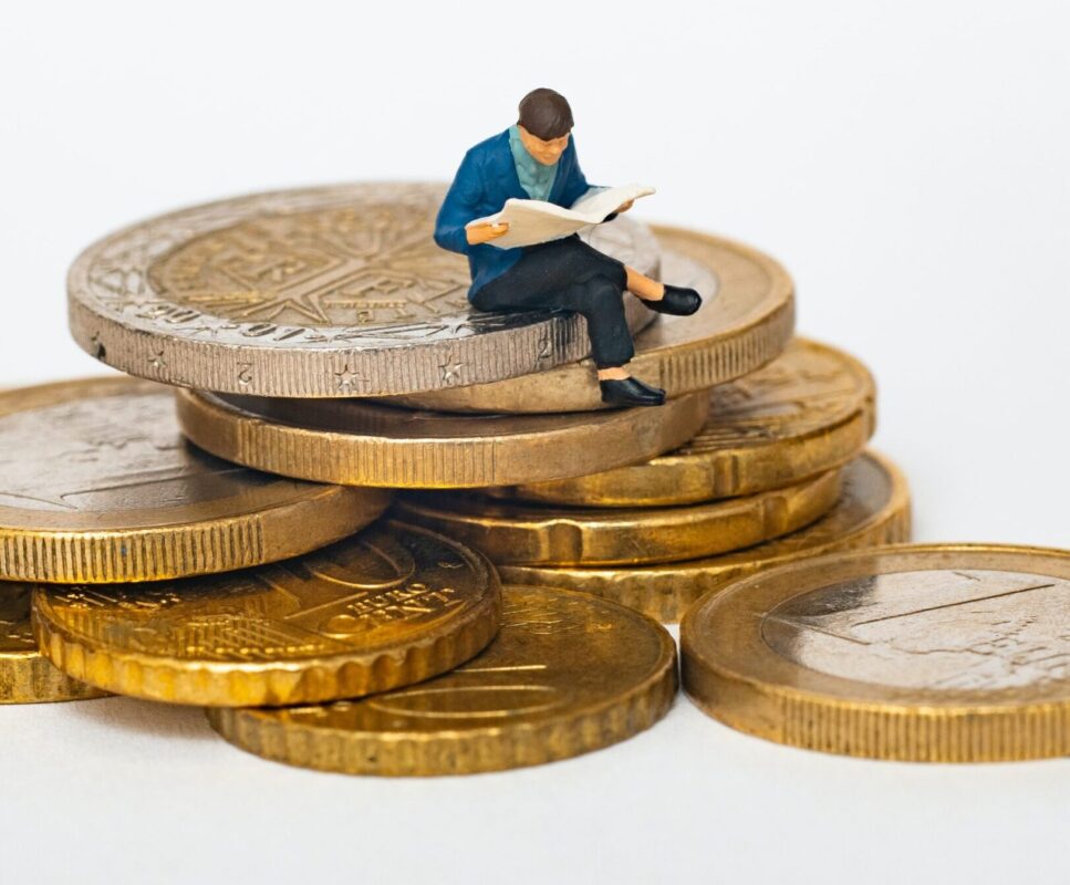 man zit op stapel munt geld en leest krant