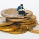 poppetje - man met krant - zit op stapel munt geld en leest krant